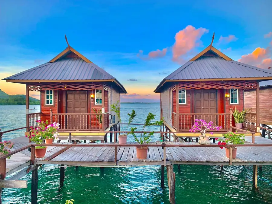A detailed wooden overwater suite featuring a prominent gable with green roofing and decorative timber fascia, embodying classic Sabahan heritage styling at Parapat Water Village Resort.