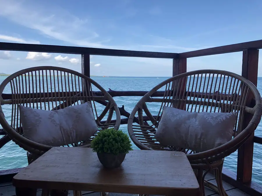 Private sunlit balcony with ocean views at Parapat Water Village Resort. An intimate over the water escape in Semporna offering a gentle sea breeze and comfortable rattan seating.